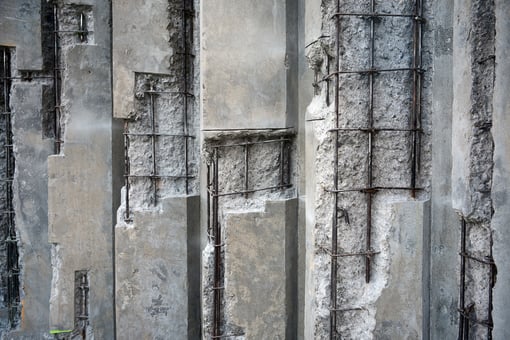 damaged-concrete-walls-exposed-steel-reinforcements-487939780