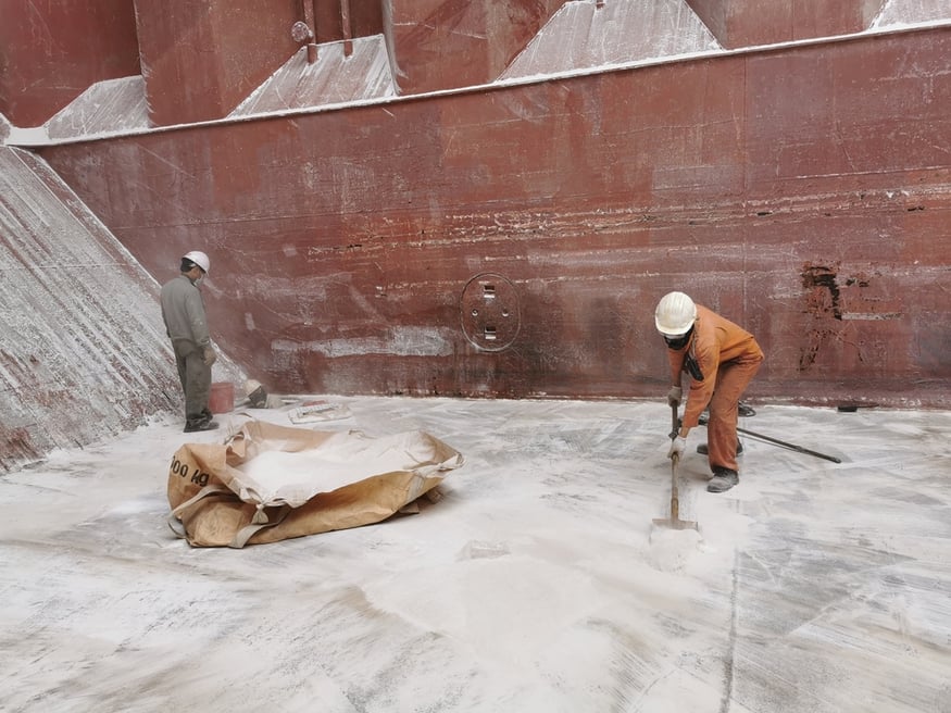 ship-crew-sweeping-alumina-cargo-residue-2096624320