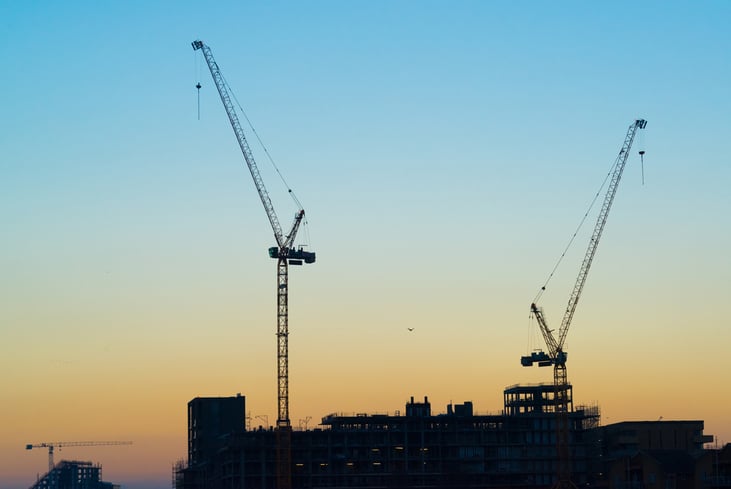 silhouettes-two-massive-construction-cranes-sky-257270695